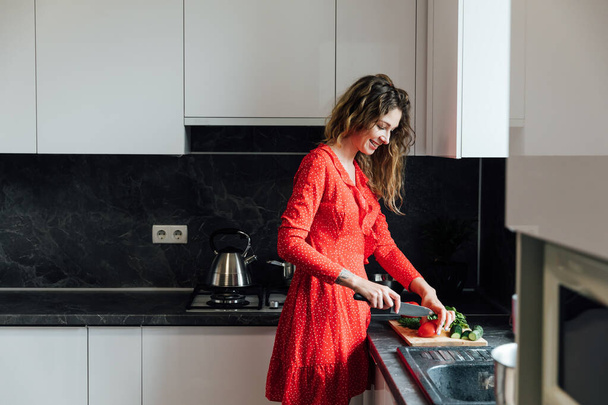 Hausfrau bereitet in der Küche einen Salat mit frischem Gemüse zu - Foto, Bild