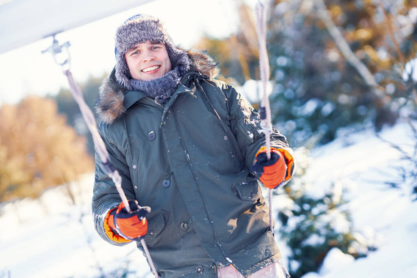 Mladý pohledný muž baví na houpačce v zimní scenérie - Fotografie, Obrázek