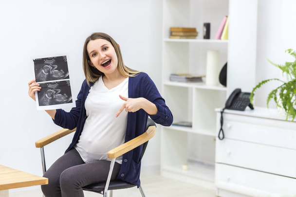 Фото усміхненої вагітної жінки з ультразвуковим результатом
. - Фото, зображення