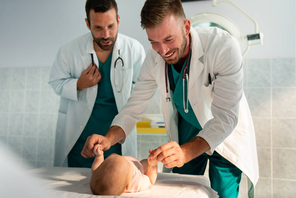 Happy pediatrician doctors examines baby. Healthcare, people, examination concept - Фото, изображение