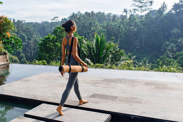 Dziewczyna z matą do jogi z tropikalnym loo - Zdjęcie, obraz