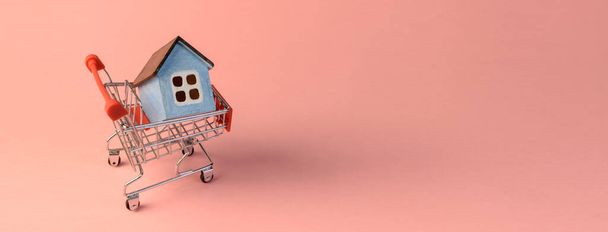 supermarket trolley and house inside on pink background, concept, banner - Fotó, kép