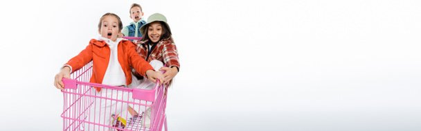 vrolijke kinderen paardrijden in roze winkelwagen op wit, banner - Foto, afbeelding