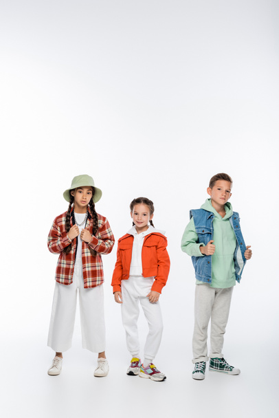 full length of trendy boy and stylish girls standing on white - Foto, afbeelding