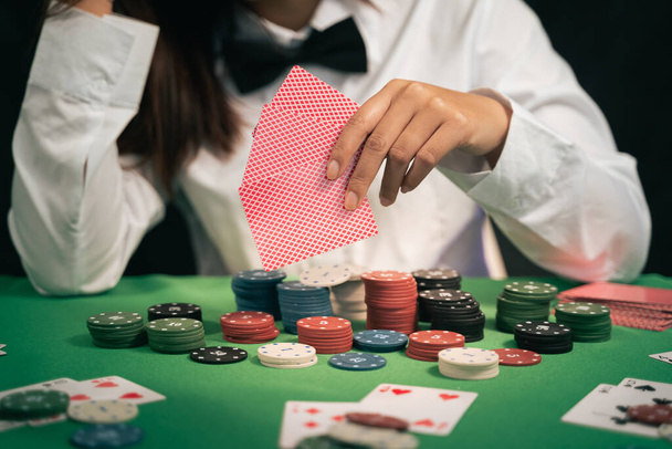 Mujer asiática distribuidor o croupier baraja cartas de póquer en un casino en el fondo de una mesa, asain mujer sosteniendo dos cartas de juego. Casino, poker, concepto de juego de póquer - Foto, imagen