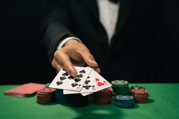 Adam satıcı ya da krupiye kumarhane kartına poker kartı karıştırıyor ve yeşil masaya da fiş koyuyor. Poker oyunu konsepti - Fotoğraf, Görsel