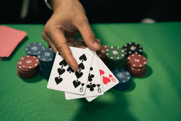 Uomo dealer o croupier mischia carte da poker in una carta da gioco del casinò, e patatine fritte sul tavolo verde. concetto di gioco di poker - Foto, immagini