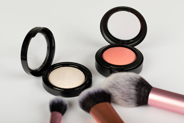 Close up picture of rose gold blush and highlighter with makeup brushes on white background - Foto, Bild