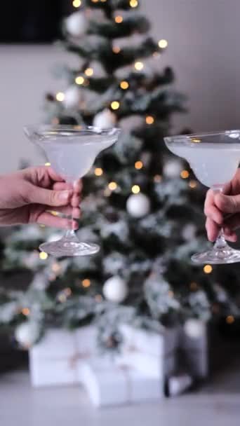 Die Menschen feiern Weihnachten und Neujahr mit Gläserklirren vor dem Hintergrund eines Weihnachtsbaums. toast - Filmmaterial, Video