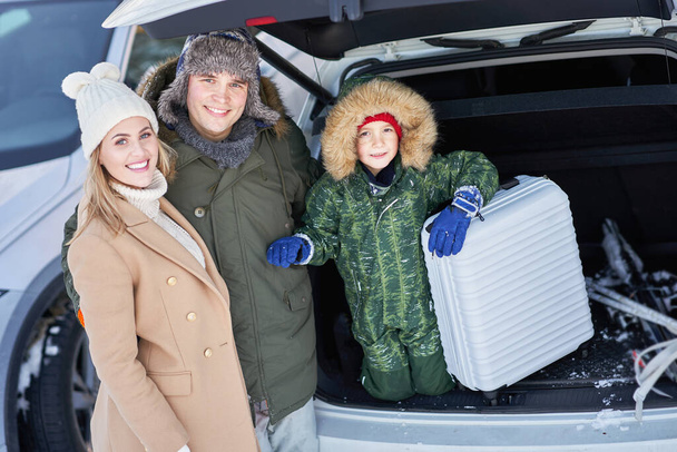 Jonge familie tijdens winterreis auto kofferbak in bacground - Foto, afbeelding