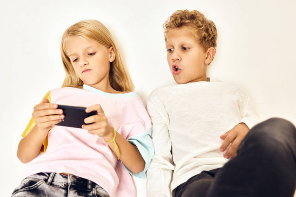 menino assistindo menina jogando telefone luz fundo - Foto, Imagem