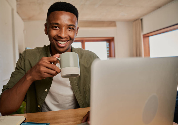 Portrait de jeune homme noir adulte tenant un café du matin, souriant à la caméra. Travailler à distance dans un appartement moderne. - Photo, image