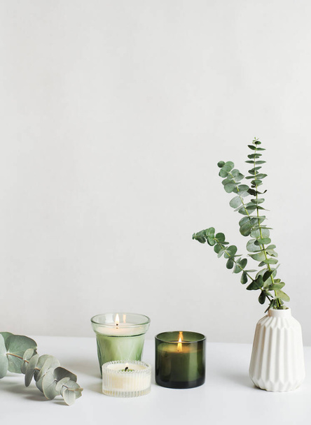Eucalyptus branches bouquet in vase and Aromatic home perfume candles, vertical shot. Home Interior comfort element and aromatherapy. copy space. - Foto, Imagem
