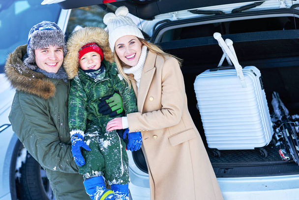 Giovane famiglia durante il viaggio invernale tronco d'auto in bacground - Foto, immagini