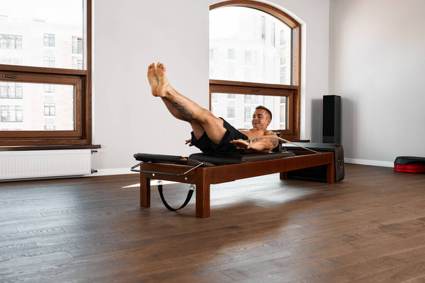 Pilates reformer workout exercises man at gym indoor. - Фото, изображение