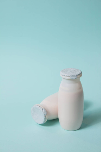 Botellas con probióticos y prebióticos bebida láctea sobre fondo azul claro. - Foto, Imagen