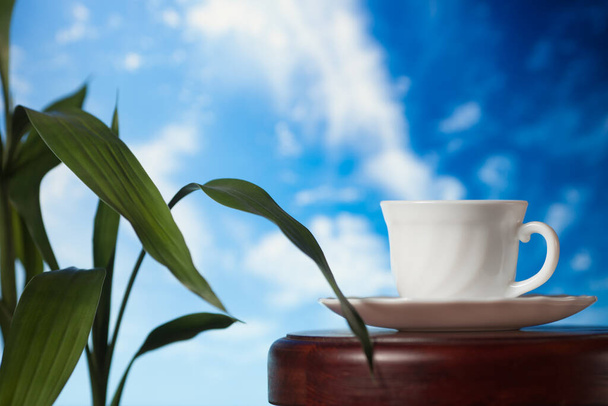 White cup of coffee or tea with steam on a wooden table on a background of blue sky - Φωτογραφία, εικόνα