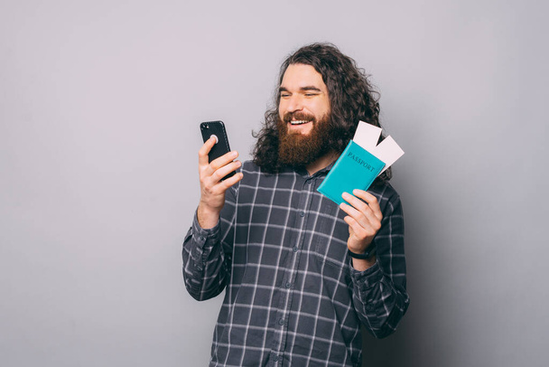 Cheerful man with tickets browsing smartphone - Foto, Bild