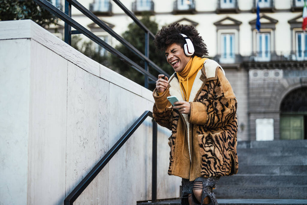 Счастливый молодой афроамериканец, получающий удовольствие от использования мобильного смартфона на открытом воздухе - образ жизни и технологическая концепция нового поколения молодежи - Фото, изображение