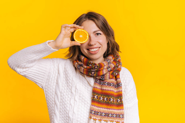 Zufriedene Frau bedeckt Auge mit Orange - Foto, Bild