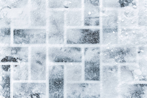 Top aboe overhead view of stone slab tiled pavement covered with snow cold winter day. Footprints on slippery surface. Weather forecast. Abstract winter texture background. Copyspace place for text - Photo, Image