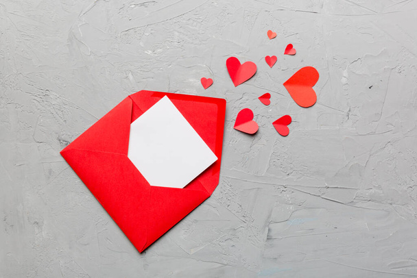 Red paper envelope with empty white card and heart on colored background. top view valentines day concept. - Φωτογραφία, εικόνα
