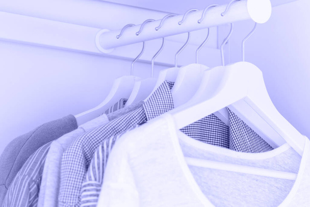 Witte garderobe met violette shirts en blouses opknoping op hangers. - Foto, afbeelding