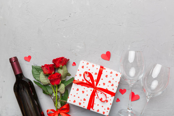 Valentýnská kompozice s červeným vínem, růžovou květinou a dárkovou krabicí na stole. Pohled shora, plochý. Koncept dovolené. - Fotografie, Obrázek