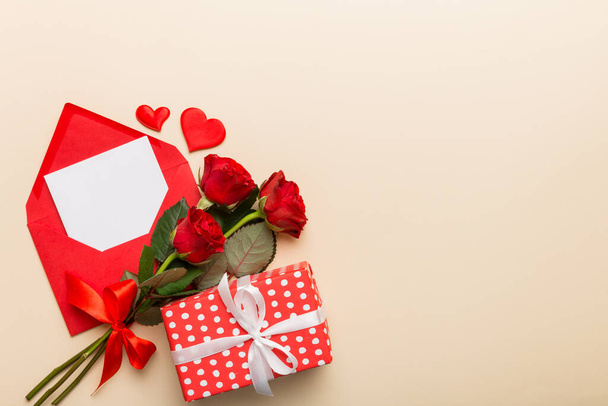 エンベロープ、バラの花とテーブルの上に赤いハートとバレンタインデーの組成。トップビュー、フラットレイアウト。休日のコンセプト. - 写真・画像