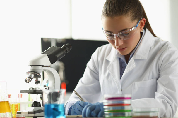 Trabajador químico concentrado anota pensamientos sobre proyecto de investigación en laboratorio - Foto, imagen