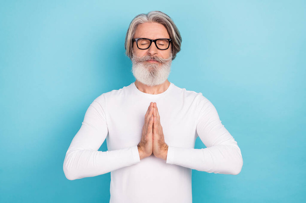 Portrait of attractive peaceful grey-haired man meditating hoping isolated over vivid blue color background - Fotografie, Obrázek