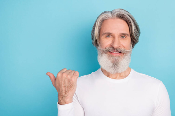 Portrait of attractive cheerful grey-haired man demonstrating copy space ad look idea isolated over bright blue color background - Fotografie, Obrázek