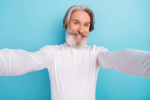 Self-portrait of attractive cheerful grey-haired man good mood isolated over bright blue color background - Foto, Imagem