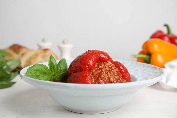Delicious stuffed pepper with basil in bowl on white table, space for text - Foto, Imagem