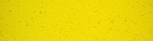 ελαφριά κίτρινη τσιμεντένια υφή. σχέδιο στον τοίχο. κίτρινο σοβά με μαύρες κουκίδες. banner για τοποθέτηση στο χώρο του ξενοδοχείου - Φωτογραφία, εικόνα