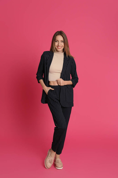 Full length portrait of beautiful young woman in fashionable suit on pink background. Business attire - Valokuva, kuva