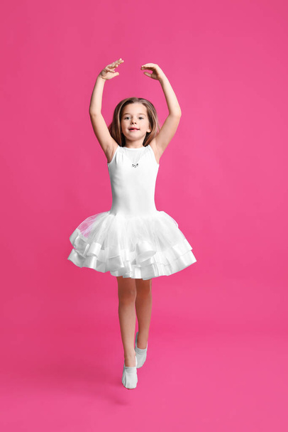 Cute little girl in white dress dancing on pink background - Foto, afbeelding