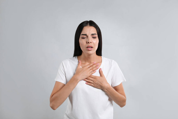 Young woman suffering from breathing problem on light background - Foto, imagen