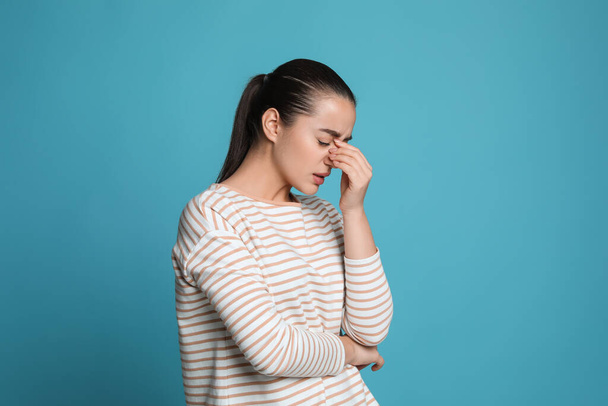 Young woman suffering from headache on light blue background - Φωτογραφία, εικόνα