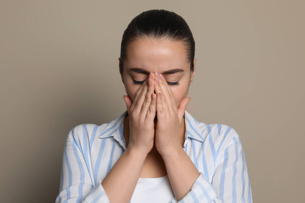 Young woman suffering from headache on beige background - Фото, зображення