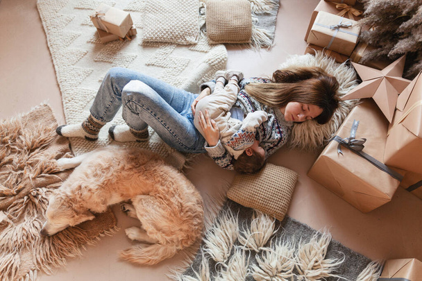 mother with child lying on floor with retriever dog in christmas decorated room - Fotoğraf, Görsel