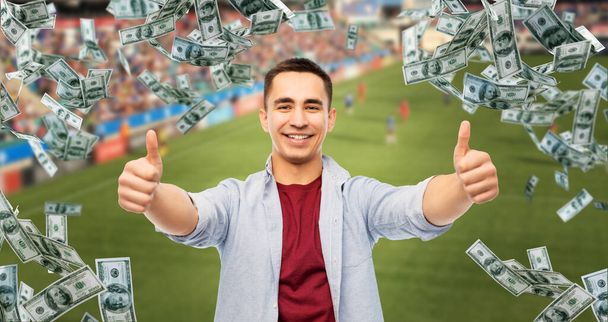 man showing thumbs up over money on football field - Valokuva, kuva