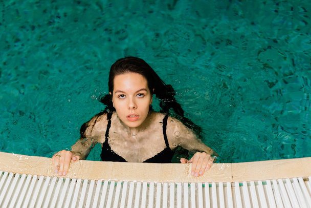 Portrait of beautiful woman in swimwear relaxing in a swimming pool spa. - Photo, Image