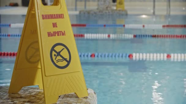Προσοχή σημάδι κοντά στην πισίνα - δεν βουτιά στο νερό - ένα άτομο που βουτά στο παρασκήνιο - Πλάνα, βίντεο