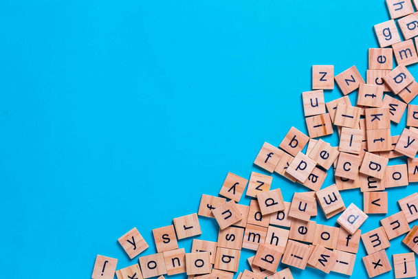 Englisches Alphabet aus quadratischen Holzfliesen mit dem englischen Alphabet auf blauem Hintergrund. Das Konzept der Denkentwicklung, der Grammatik. - Foto, Bild
