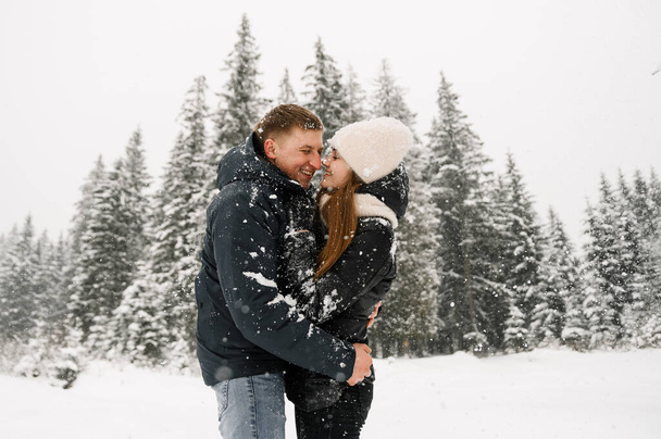 Loving couple cuddling on a winter walk. Young family having fun in the frosty forest. Romantic date in winter time. Winter lovestory - Photo, image