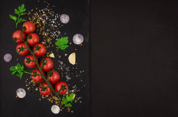 Pomidory wiśniowe na winorośli na czarnym tle - Zdjęcie, obraz