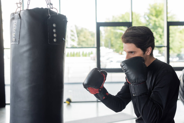 Boxer training with punching bag in sports center  - Photo, Image