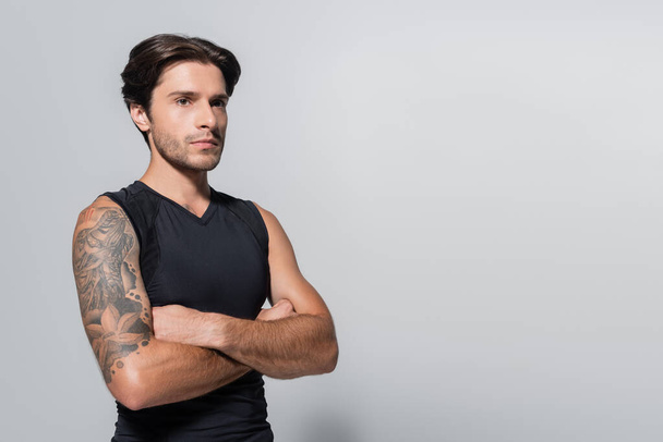 Tattooed sportsman crossing arms on grey background - Foto, immagini