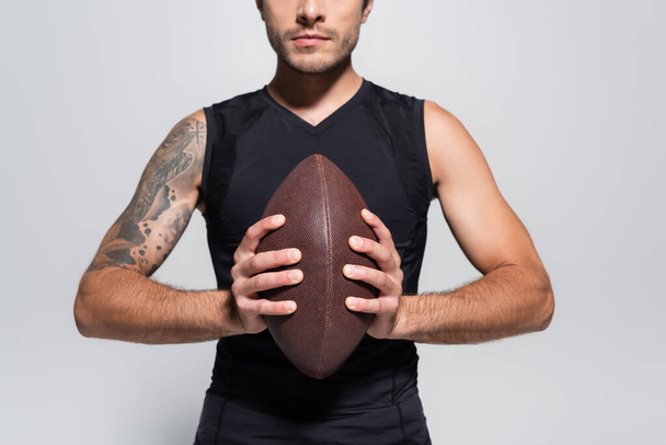 Cropped view of sportsman holding rugby ball isolated on grey  - Фото, изображение